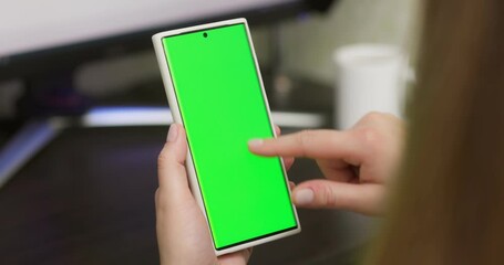 Woman using smartphone in vertical mode with green mock-up screen
