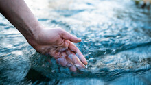 A Female Hand Touching The River Water