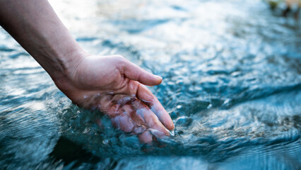 a female hand touching the river water