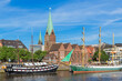 Cityscape of Bremen with old architecture, historical wooden sailing ships and barge floating along the river Weser. Bremen, Germany, July 15, 2021