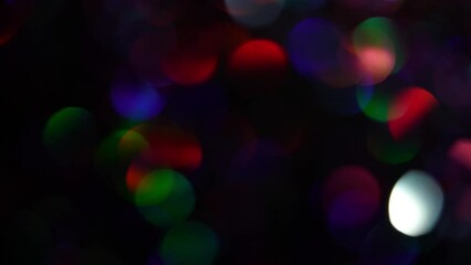 Wall Mural - Flowing neon bokeh lights. Colorful glowing rainbow confetti transition in front of a black background. Animated neon blurred bokeh background with blue, purple, green and magenta colored dots on dark