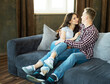 © Raisa Kanareva - Young beautiful couple is sitting on the couch and hugging. Happy family life.