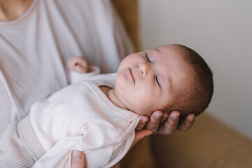 Portrait of baby sweet sleeping on mother's hands. Loving mom carying of her newborn baby at home. Mother hugging her little 1 months old girl.