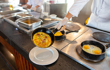 Wall Mural - The cook is frying scrambled eggs in a frying pan in the kitchen.