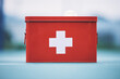 © Azee Jacobs/peopleimages.com - First aid, box and medical equipment for health emergency, response and treatment kit isolated in a blurred background. Red, cross and safety or medicine on a table for fast healthcare or cure