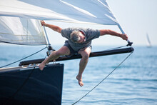 Man At Bow Of Sailboat Trying To Fix Furling System On Head Sail, Arcachon Bay, France