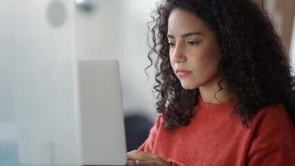 Young busy latin business woman office worker, company employee or student using laptop, typing on computer sitting in office elearning course looking at pc, thinking on data operations plan.