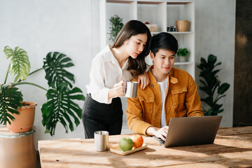 Two Asian business workers talking on the smartphone and using laptop at the home office.