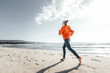 © Westend61 - Mature woman jogging on shore at beach