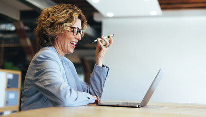 Wall Mural - Business woman smiles as she talks to an associate on a mobile phone