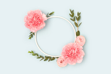 Wall Mural - round frame made of pink rose, carnation flowers and green eucalyptus branches on a blue background.