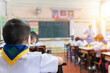 © jittawit.21 - Back view Elementary school students learning in the classroom. Students Sitting At Desk While Teacher Teaching In Classroom.