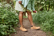 © Seventyfour - Low section shot of black woman spaying legs with bug repellant standing in grass and travelling in nature