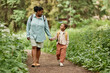 © Seventyfour - Full length portrait of happy mother and daughter walking on nature trail together holding hands