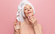 Hydration and refreshment. Beautiful middle-aged woman applying face toner over pink studio background. Concept of natural beauty, face skin care, cosmetology and cosmetics, health