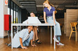 Female teacher and naughty student pupils : Young beautiful teacher sits desk without complaining in the school library with boys and girls having fun sit on the table and below them mischievously.