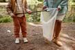 © Seventyfour - Cropped portrait of child helping clean nature and picking up plastic bottles outdoors