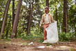 © Seventyfour - Full length portrait of smiling little girl picking up trash in nature trail, copy space