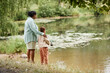 © Seventyfour - Back view of mother and daughter fishing together by lake in beautiful family bonding moment, copy space
