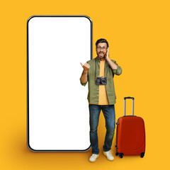 Excited man traveler pointing at big blank smartphone display, mockup