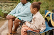 © Seventyfour - Side view portrait of black little girl holding fishing rod while enjoying camping with family