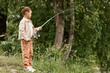 © Seventyfour - Full length side view portrait of black little girl fishing by river in nature with fishing rod bending, copy space