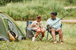 © Seventyfour - Full length portrait of black mother and daughter camping together outdoors and enjoying nature