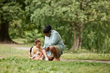 Wall Mural - Loving mother putting band aid on knee of little girl injured during nature hike, copy space 