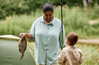 © Seventyfour - Smiling mother and daughter fishing together during camping in nature