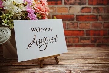 Canvas Print - Welcome August text with flower bouquet decoration on wooden and old brick wall background