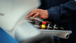 © Benixs - Close-up of African production engineer's hand with safety wear operating CNC machine in the factory. A male factory worker is programming and adjusting industrial machine to control the production.