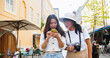 © ihorvsn - Portrait of cheerful Asian mother and daughter walking in town in good mood and looking around. Beautiful woman traveler in hat with photo camera. Young female tourist typing on smartphone in city