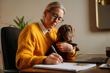 caucasian female business woman working from home holding pet dog