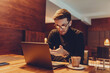© Minet - Happy young businessman working on a laptop in a cafe