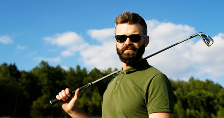 Portrait shot of Caucasian handsome male player in the sunglasses with a club turning his head to the camera. Outdoor. Close up