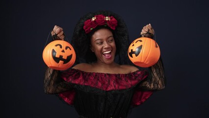 Sticker - African american woman wearing katrina costume holding halloween pumpkin baskets over isolated black background