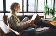 © BullRun - Focused woman reading papers on couch