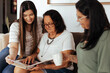 © kleberpicui - Three generation family looking at old photo album in living room.