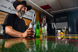 © Rafa - hombre barman con gorro de vaquero preparando un cóctel azul en la barra del bar