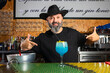 © Rafa - hombre barman con gorro de vaquero preparando un cóctel azul en la barra del bar