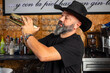 © Rafa - hombre barman con gorro de vaquero preparando un cóctel azul en la barra del bar