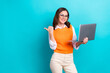 © deagreez - Photo of young positive satisfied businesswoman wear office uniform eyewear hold laptop direct finger empty space isolated on cyan color background