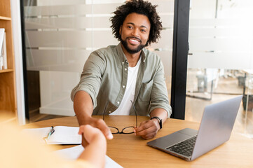 Pleasure doing business with you. Handsome positive businessman looking at the colleague out of view, they shaking hands. Collaboration of business partners, workteam, support and agreement concept