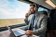 © Dusko - Handsome businessman is having a good time while traveling by high-speed train. He is using laptop computer and wireless headphones for online communication, gaming and entertainment.