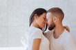 © Iona - Young caucasian couple in white t-shirts embracing at bathroom. Brunette hispanic girl kissing beardy husband at home. Newlyweds enjoying vacation together. Relationship, family, dating.