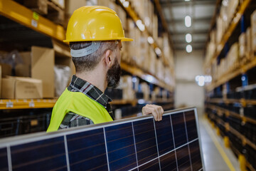 Poster - Rear view of warehouse worker carring solar panel.