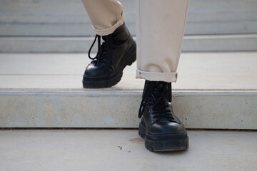 Detail of black boots of man walking down stairs.