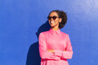 © VISTA by Westend61 - Happy woman wearing sunglasses with arms crossed in front of wall