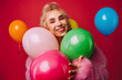 © VISTA by Westend61 - Happy senior woman playing with balloons against red background