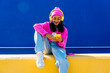 © VISTA by Westend61 - Smiling woman with headphones using smart phone on wall